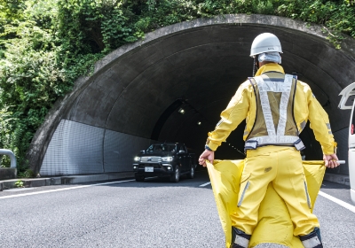 トンネル付近で男性社員が車を交通規制する様子